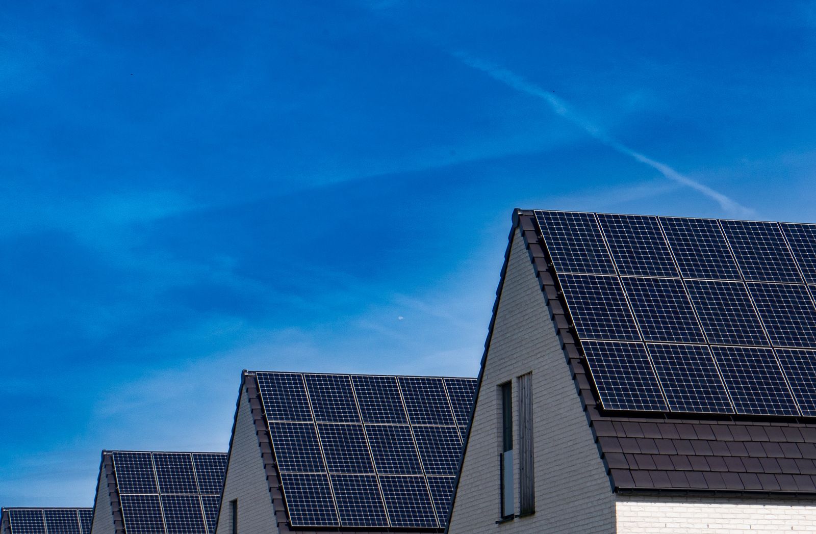 Rows of homes with rooftop solar against a blue sky